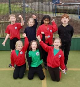Seven KS2 pupils are pictured cheering together in a group photo, after having played a game of Hockey.