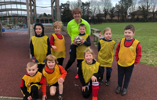 Marden pupils are seen smiling for a group photo, wearing yellow vests, after having played a Football game with Greenfields.
