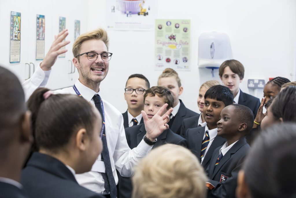 Young male staff member seen talking to students in a group.